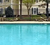 A pool in front of a building with a black fence around it.